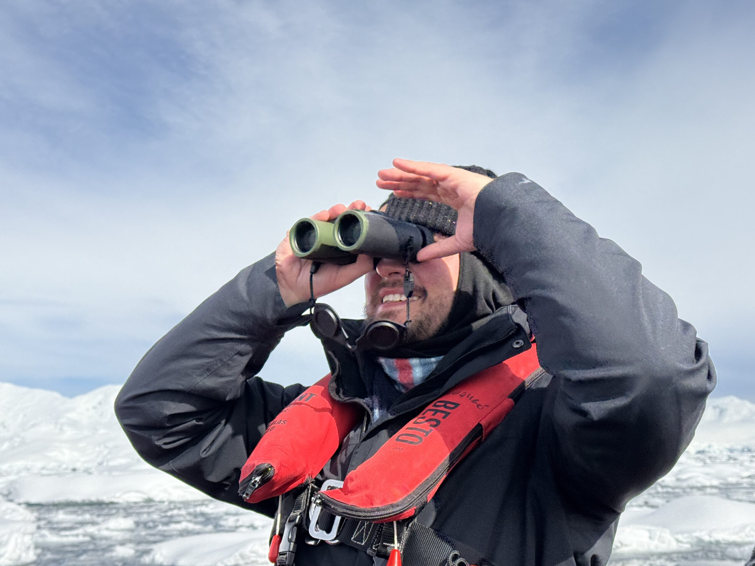 Mężczyzna patrzący przez lornetkę na Antarktydzie